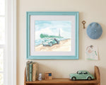 A framed watercolor art print depicting a vintage car on a beach with the Eiffel Tower in the distance, styled on a beige wall above a wooden shelf with books, a toy car, and a blue beret.