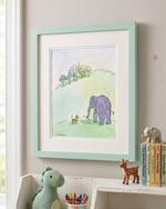 A framed watercolor art print featuring a purple elephant and a small dog in a green landscape, styled on a wall above a shelf with toys and books.