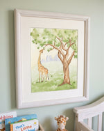 A framed watercolor art print depicting a giraffe and tree, displayed on a light green wall above a crib with baby books and a stuffed giraffe.