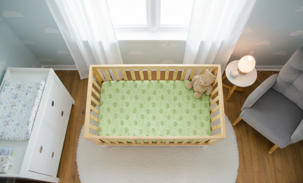 Wooden crib with green mattress cover in a nursery room